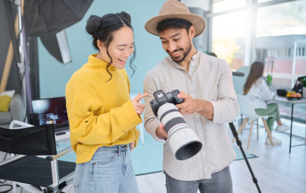 Camera, creativity and photographer talking to a model while looking at pictures from a photoshoot